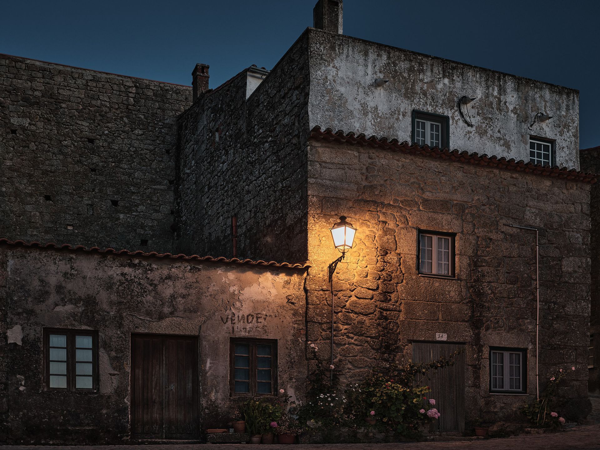 A building with a lamp on the side of it at night.