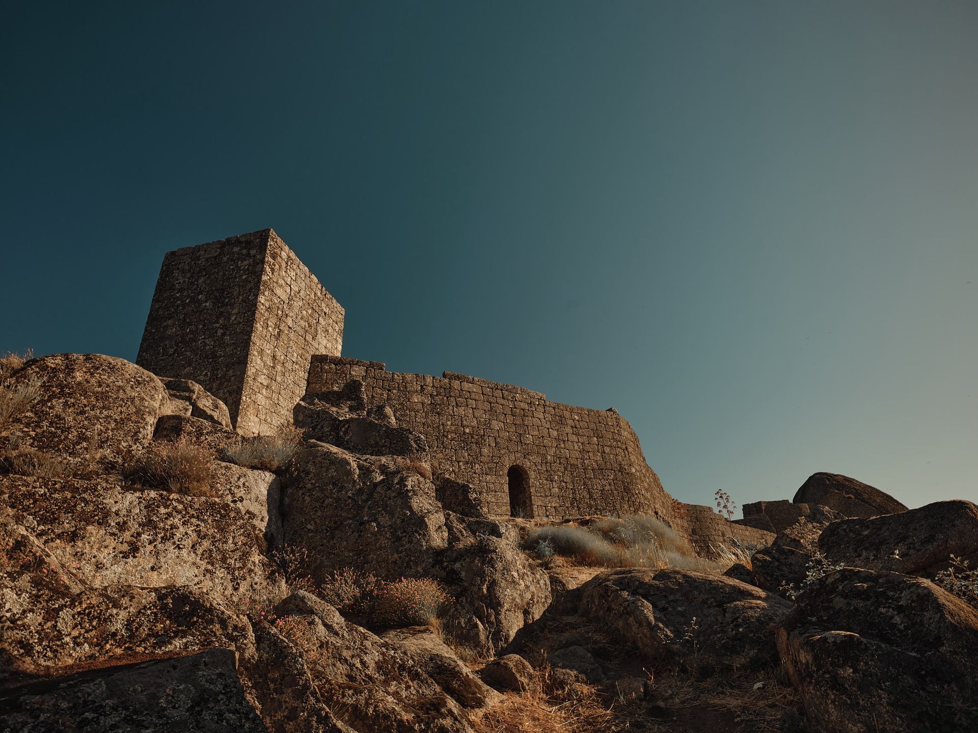 A stone building is sitting on top of a rocky hill.