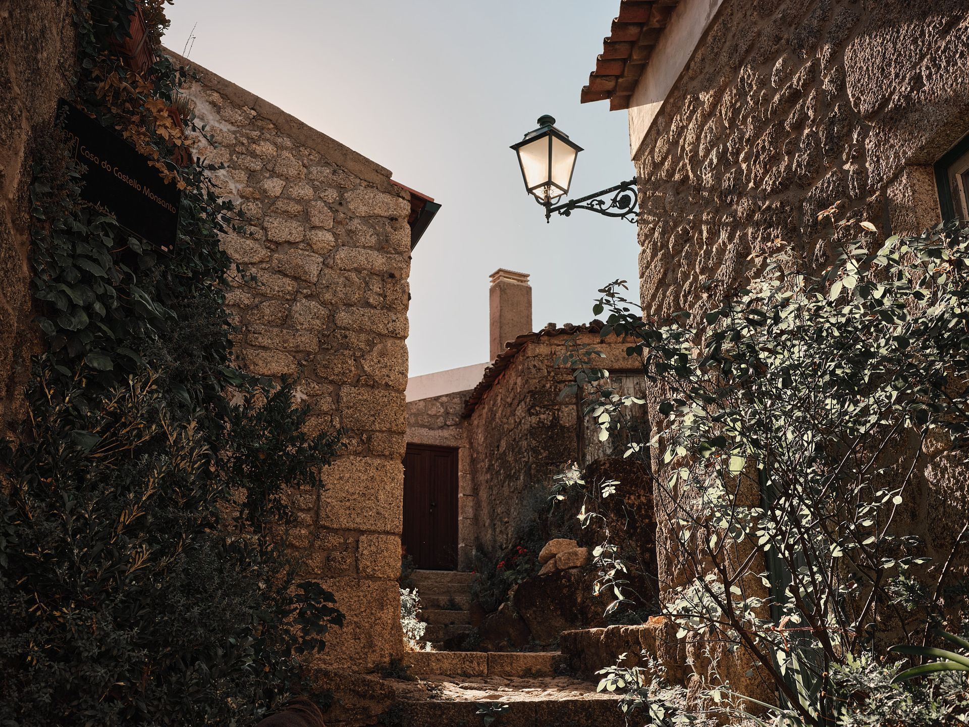 A street light is hanging from the side of a stone building.