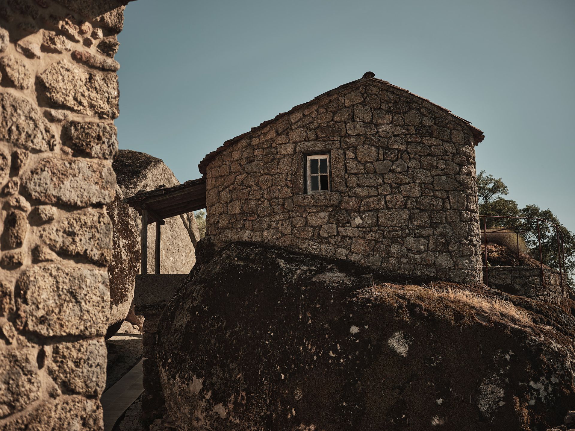 A stone house is sitting on top of a large rock.