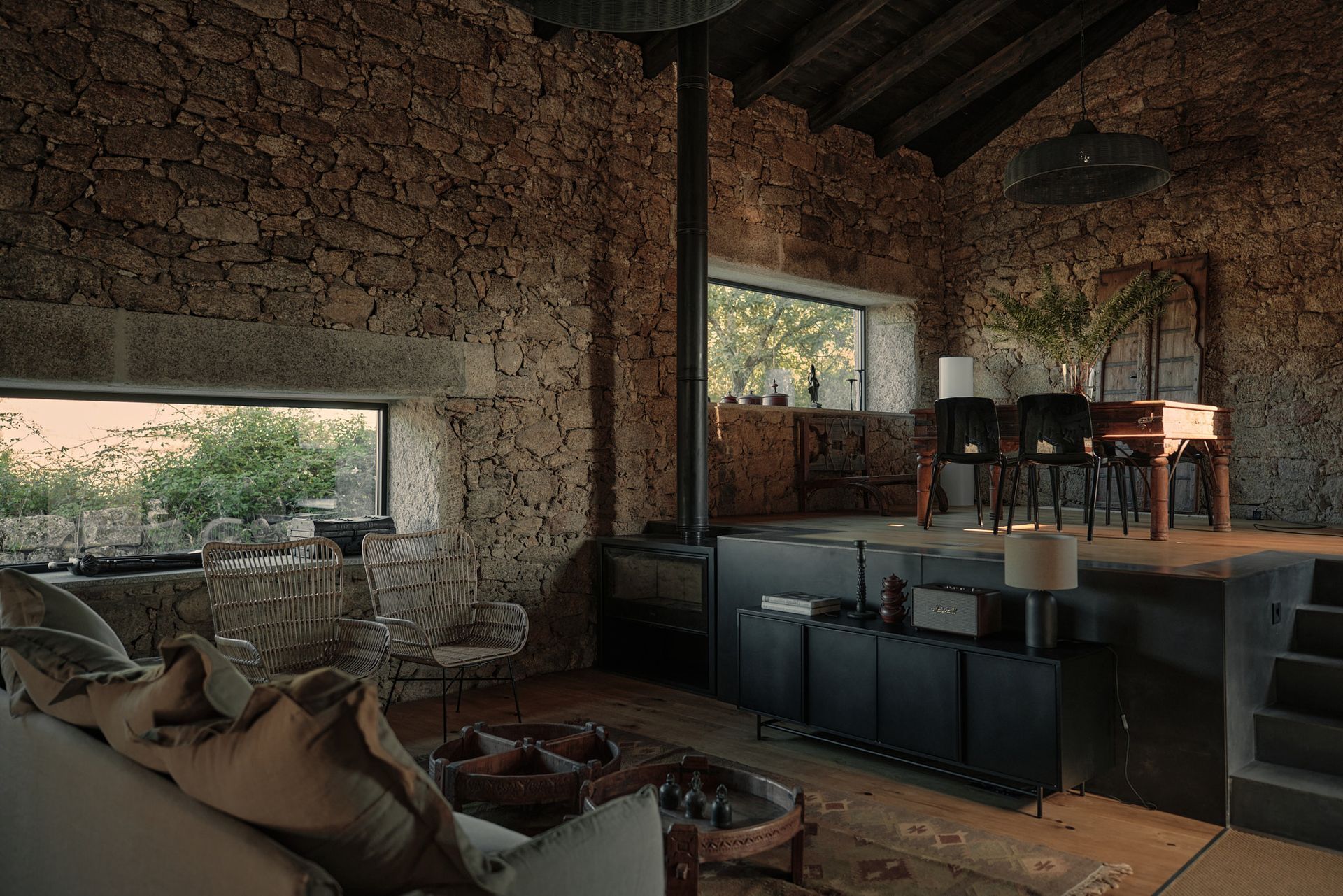 A living room with a couch , table and chairs and a stone wall.