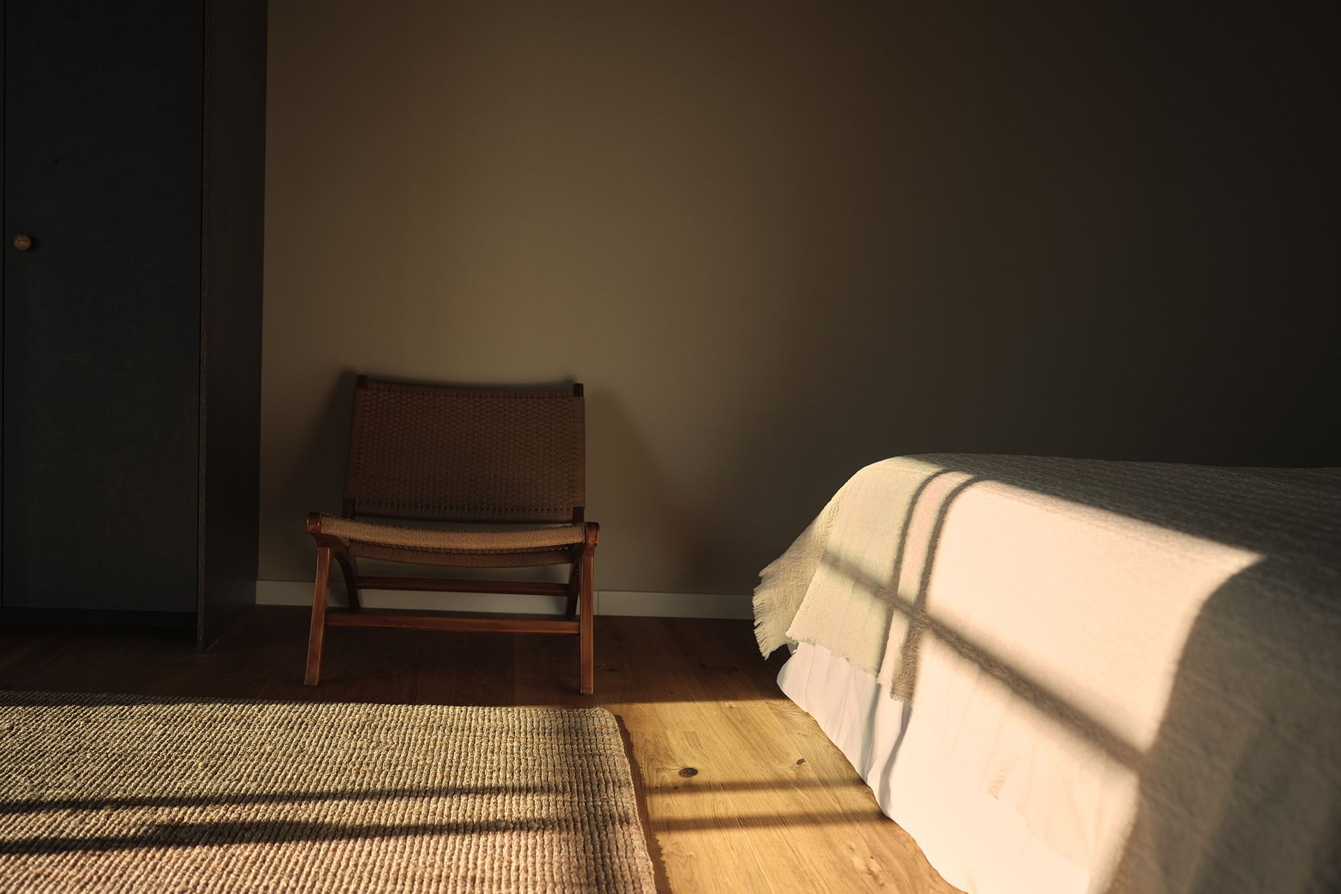 A chair is sitting in a dark room next to a bed.