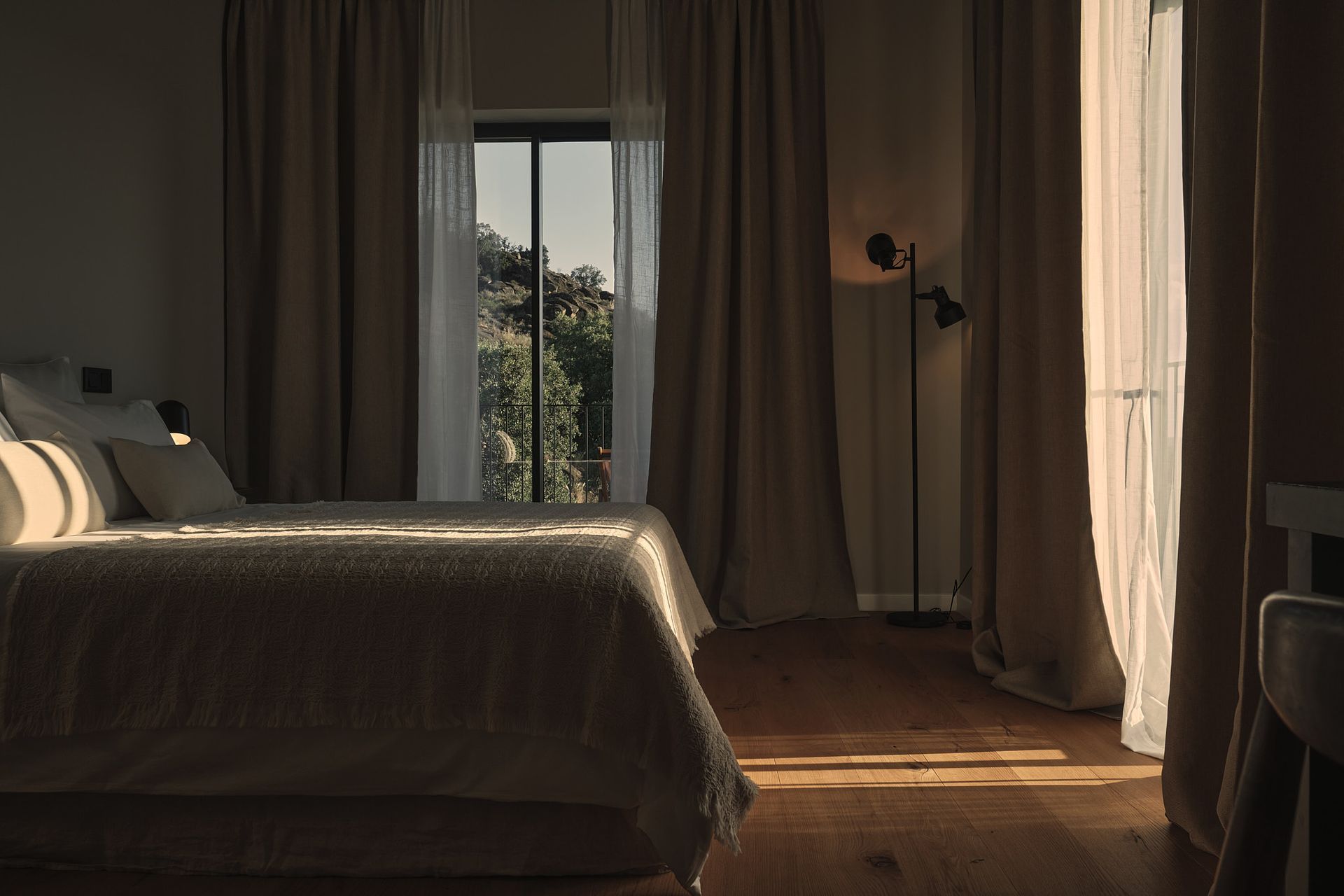 A bedroom with a bed , lamp , curtains and a window.