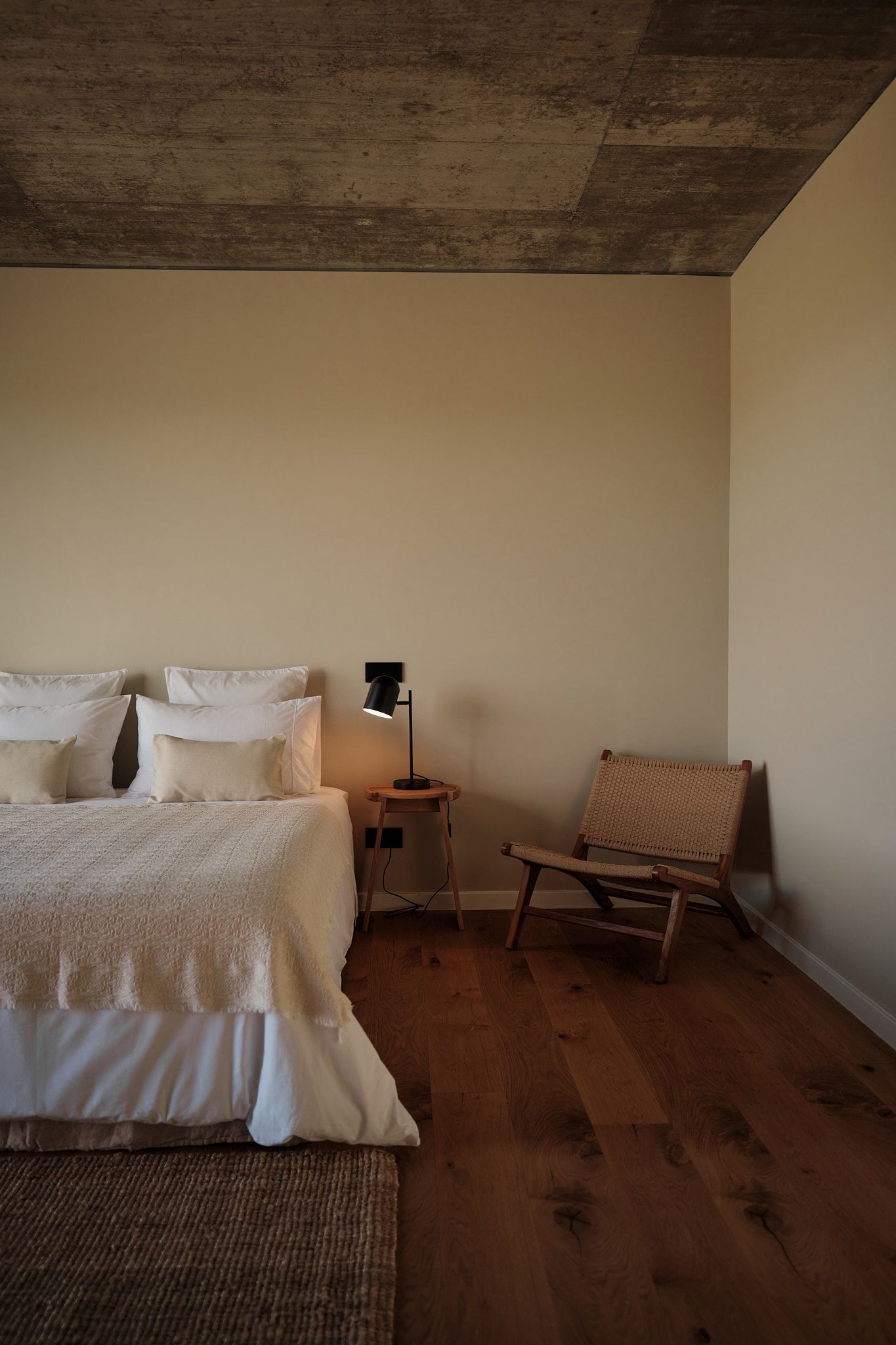 A bedroom with a bed , chair , nightstand and lamp.