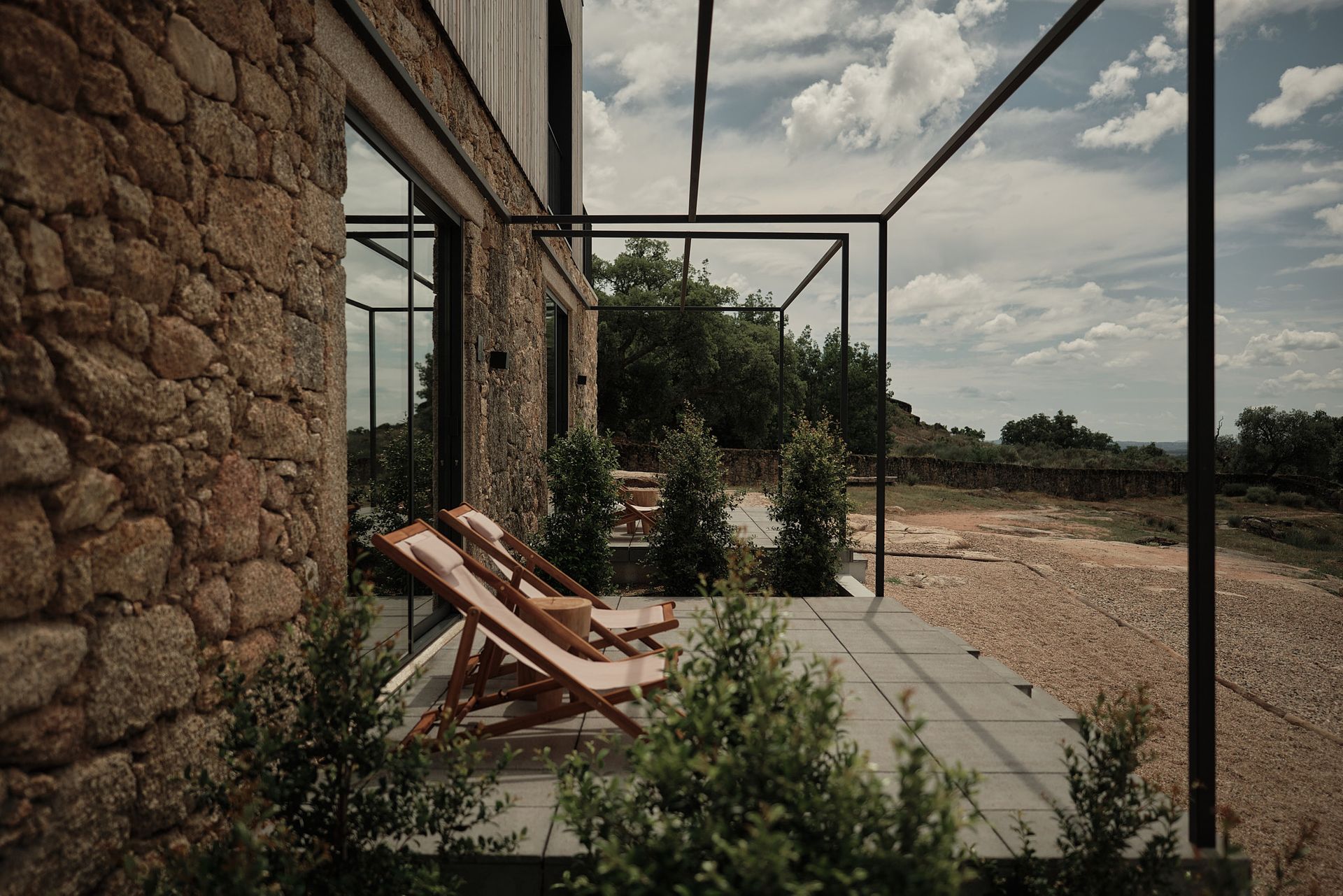 A stone building with a pergola and chairs in front of it.