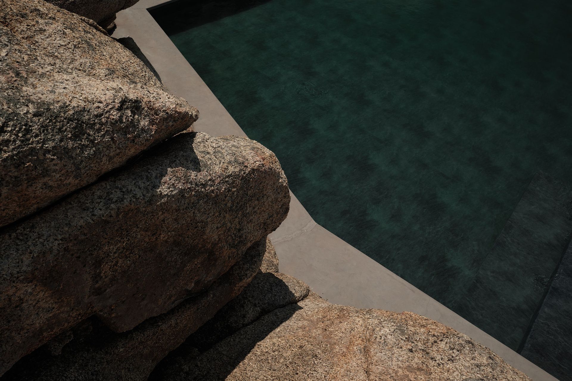 A stack of rocks sitting next to a swimming pool.