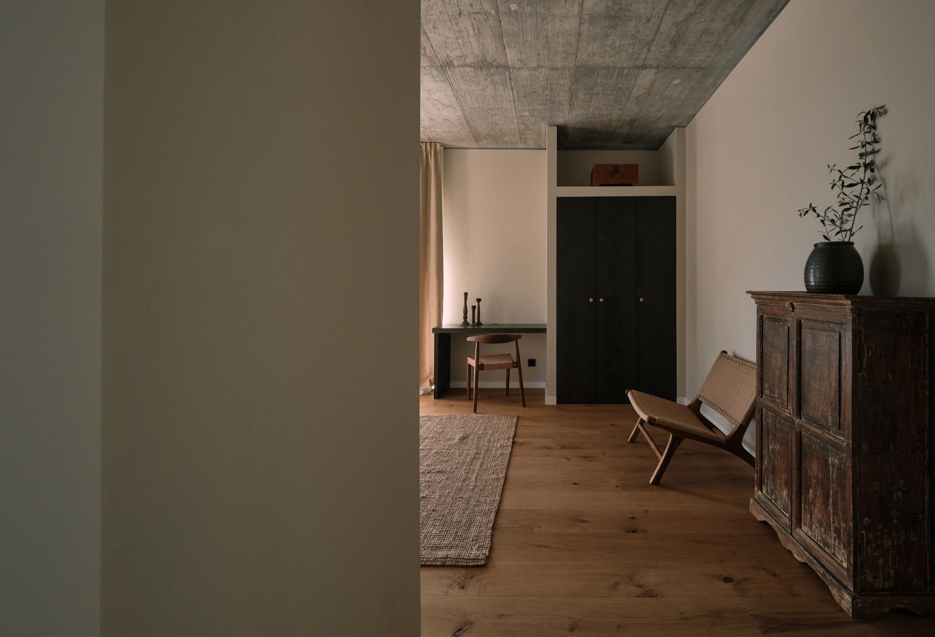 A room with a wooden floor , a chair , a desk and a dresser.