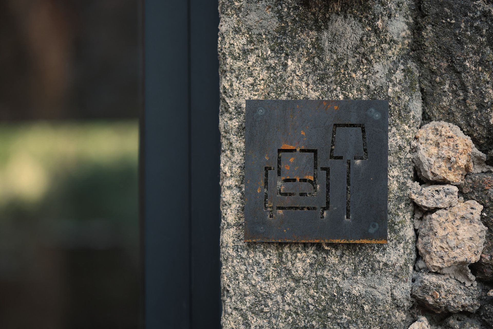 A close up of a metal sign on a stone wall.