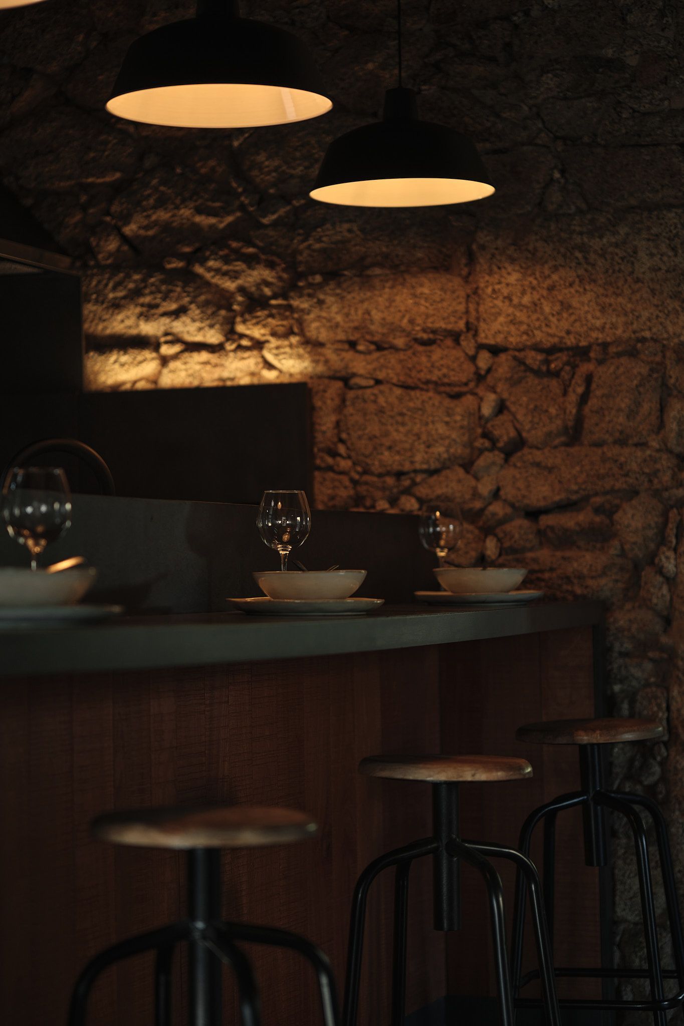 A restaurant with a stone wall and a bar with stools