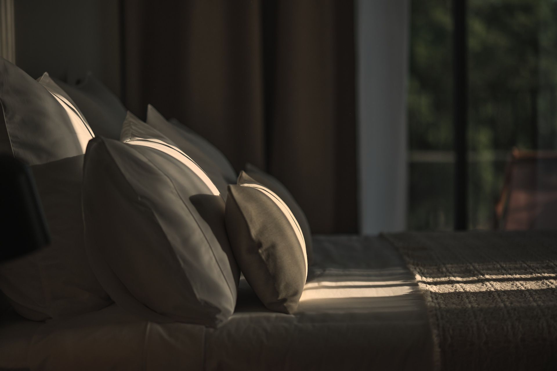 A bed with a lot of pillows in a dark room