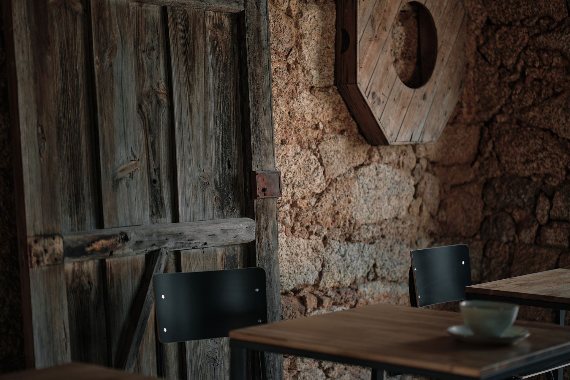 A wooden table and chairs in a room with a stone wall.