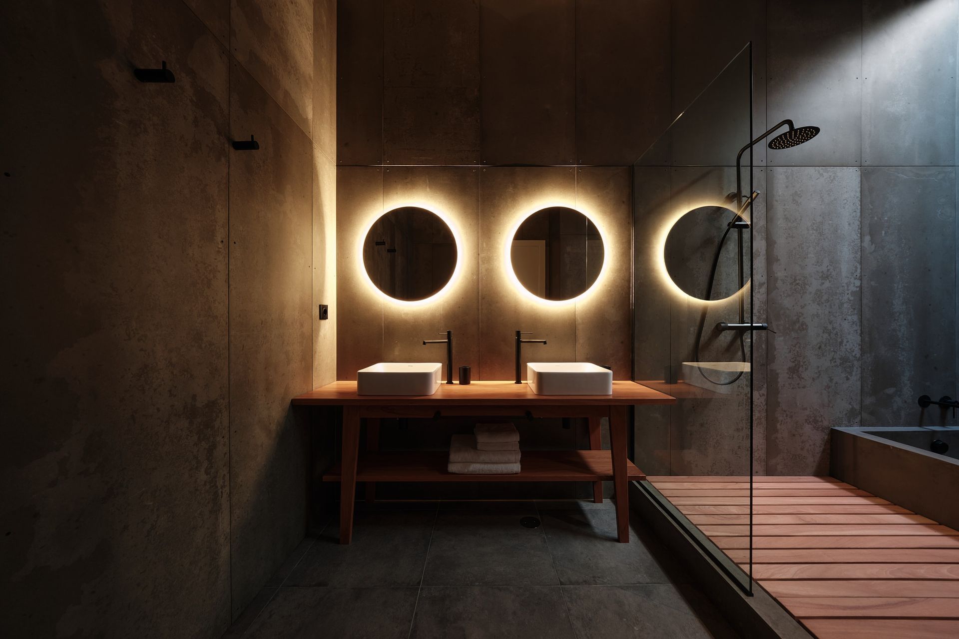 A bathroom with two sinks , two mirrors and a shower.