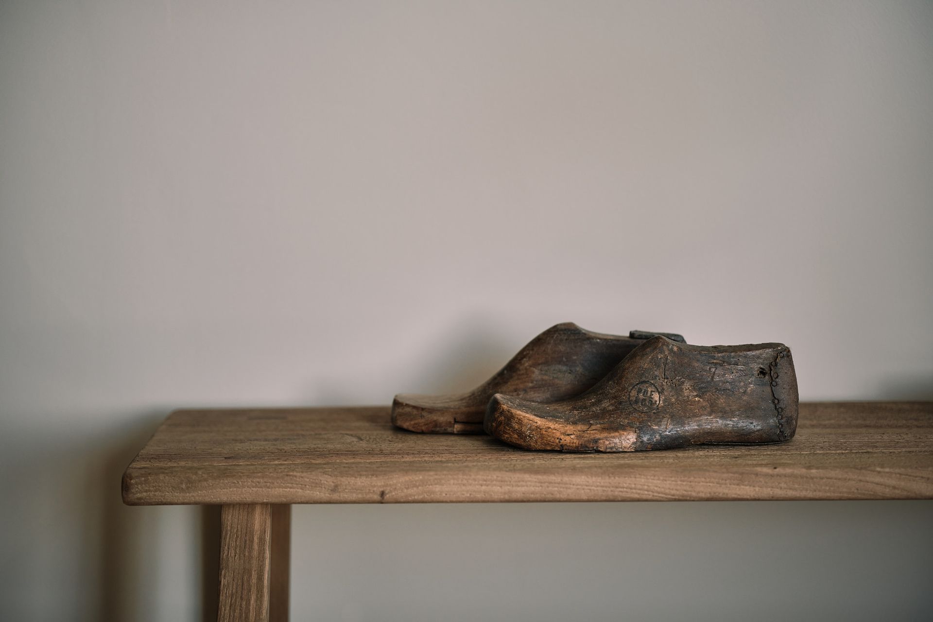 A pair of wooden shoes are sitting on a wooden table.