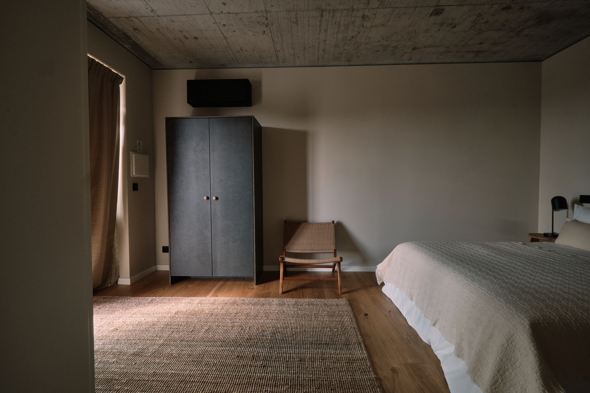 A bedroom with a bed , chair , wardrobe and rug.