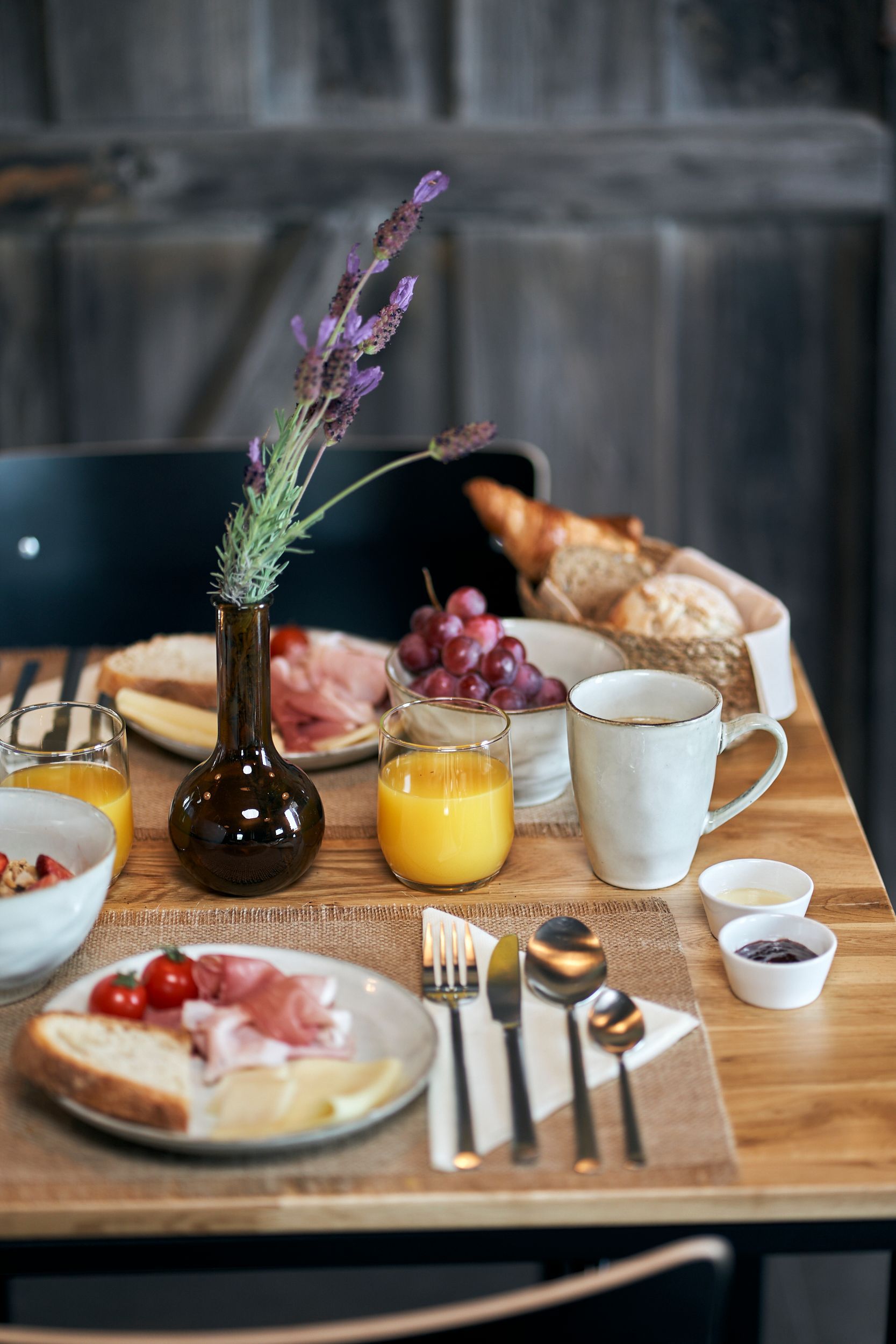A wooden table topped with plates of food and a vase of flowers.
