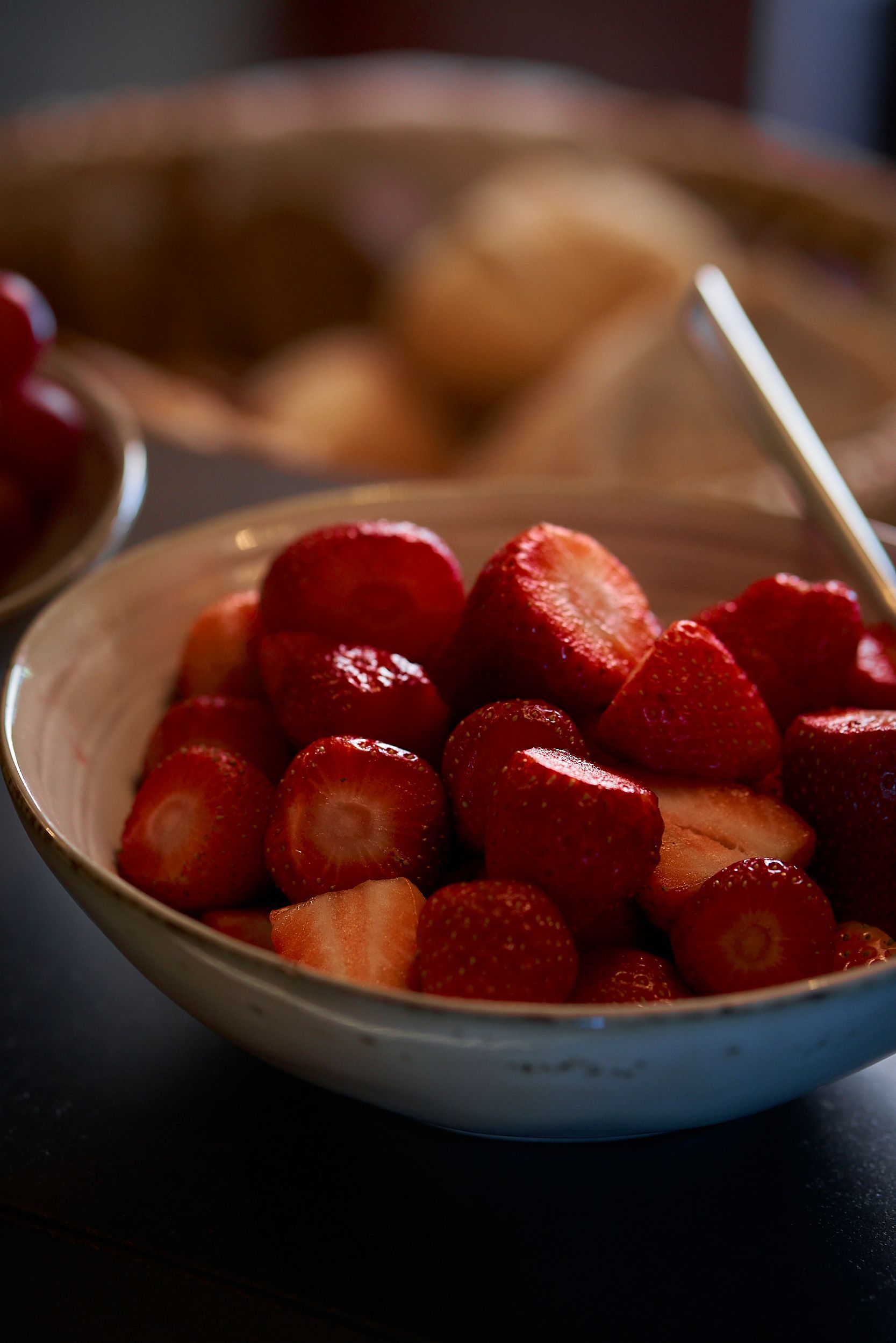 A bowl of strawberries with a spoon in it