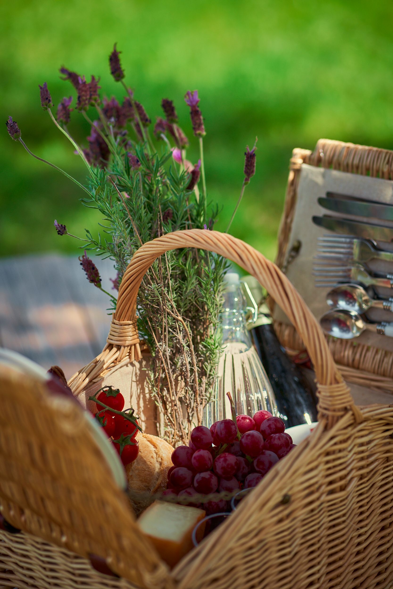 A wicker picnic basket filled with food and flowers.