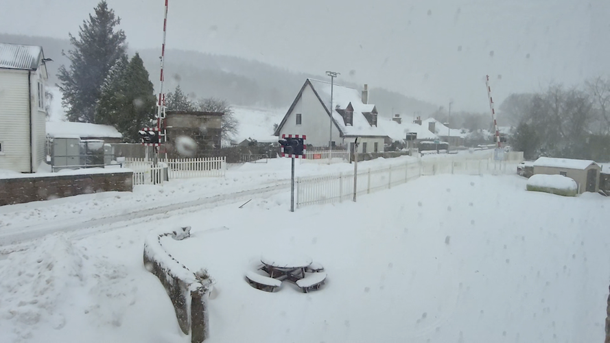 Houses and the level crossing in Insch covered in feet of snow