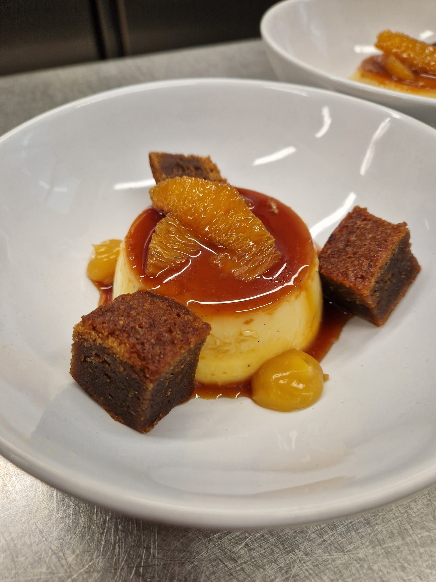 A bowl containing an orange creme caramel with cubes of sticky honey sponge