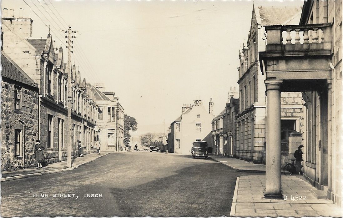 A wide street with buildings on either side including one with Grecian columns