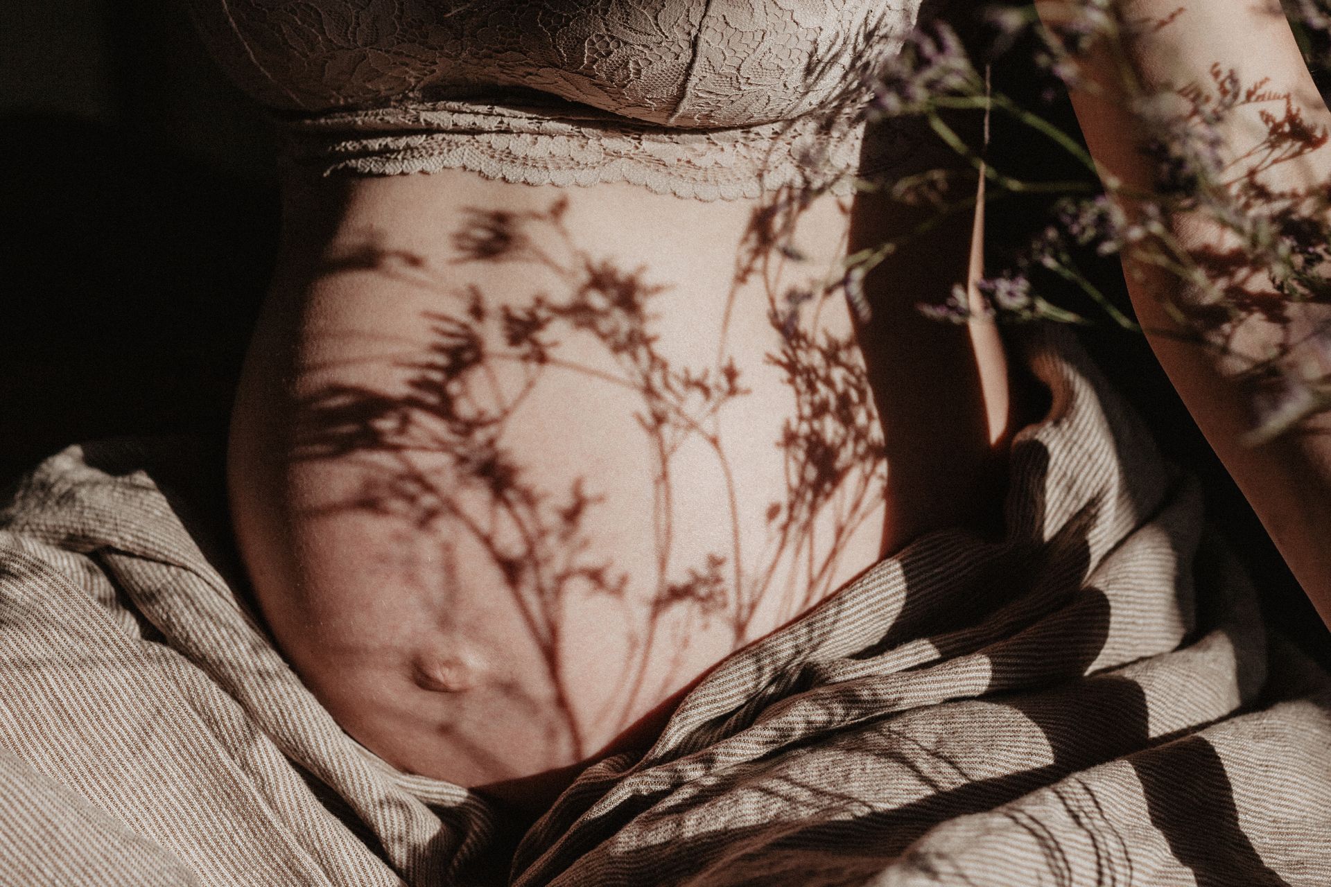 Close-up van een hals met plantenschaduwen die in warm licht over de huid vallen.