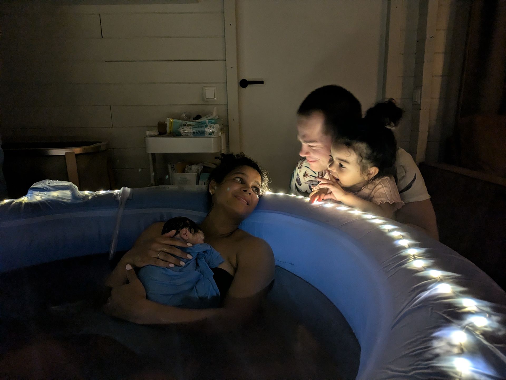 Mensen ontspannen in een oplichtend opblaasbaar bevalbad binnenshuis.