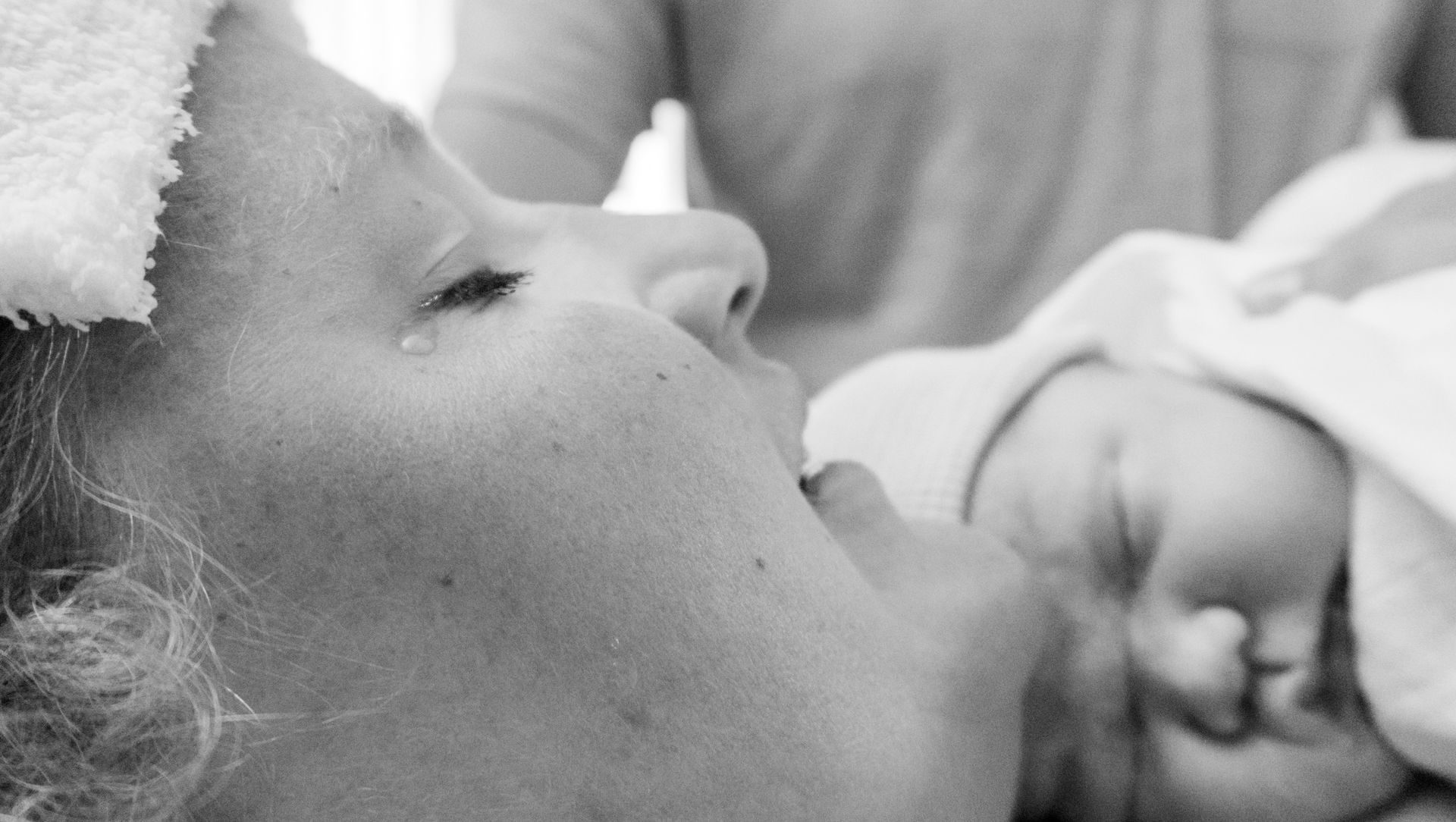 Vrouw rust met gesloten ogen en houdt een slapende baby dicht tegen haar gezicht.