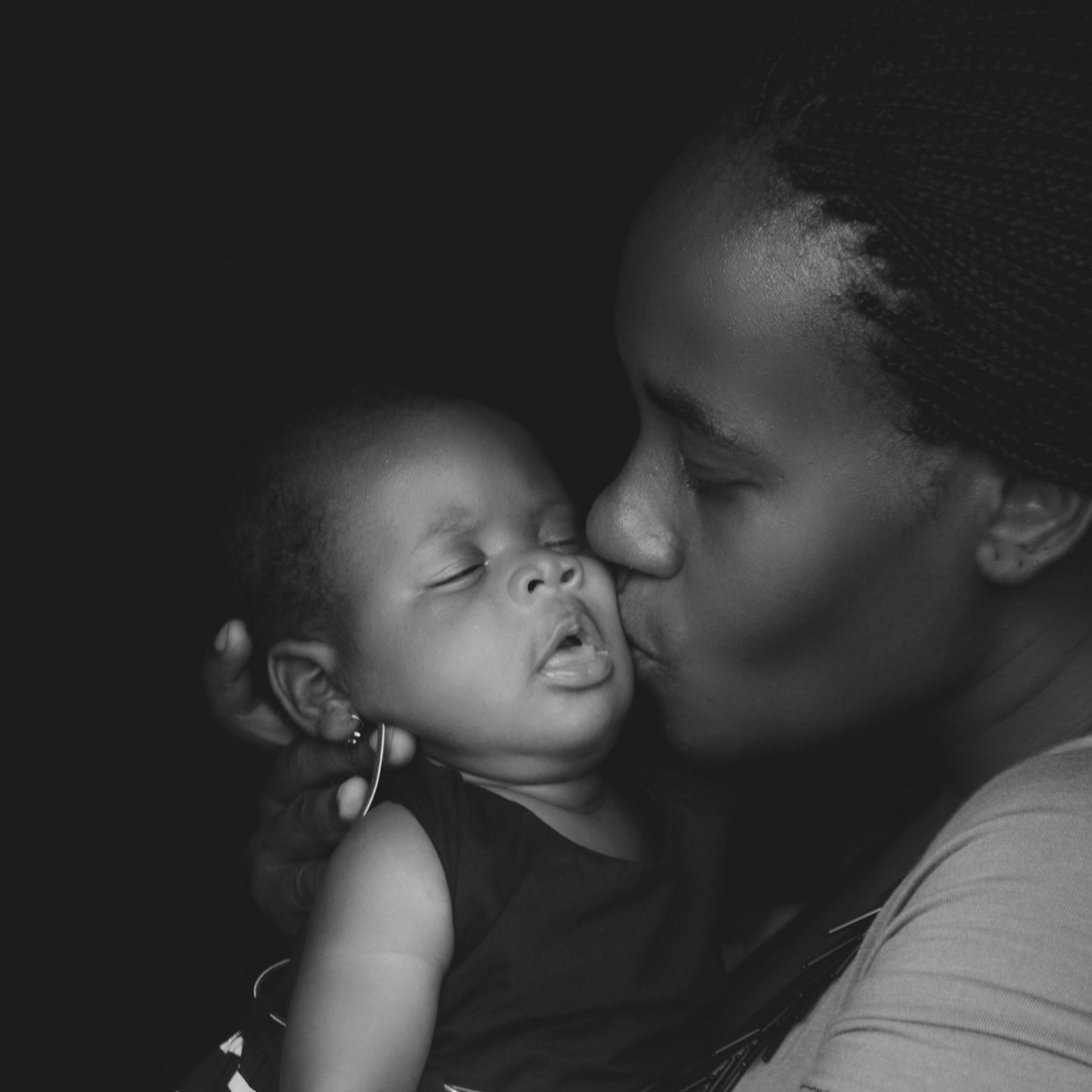 Vrouw kust teder een slapende baby in een zwart-wit close-up portret.