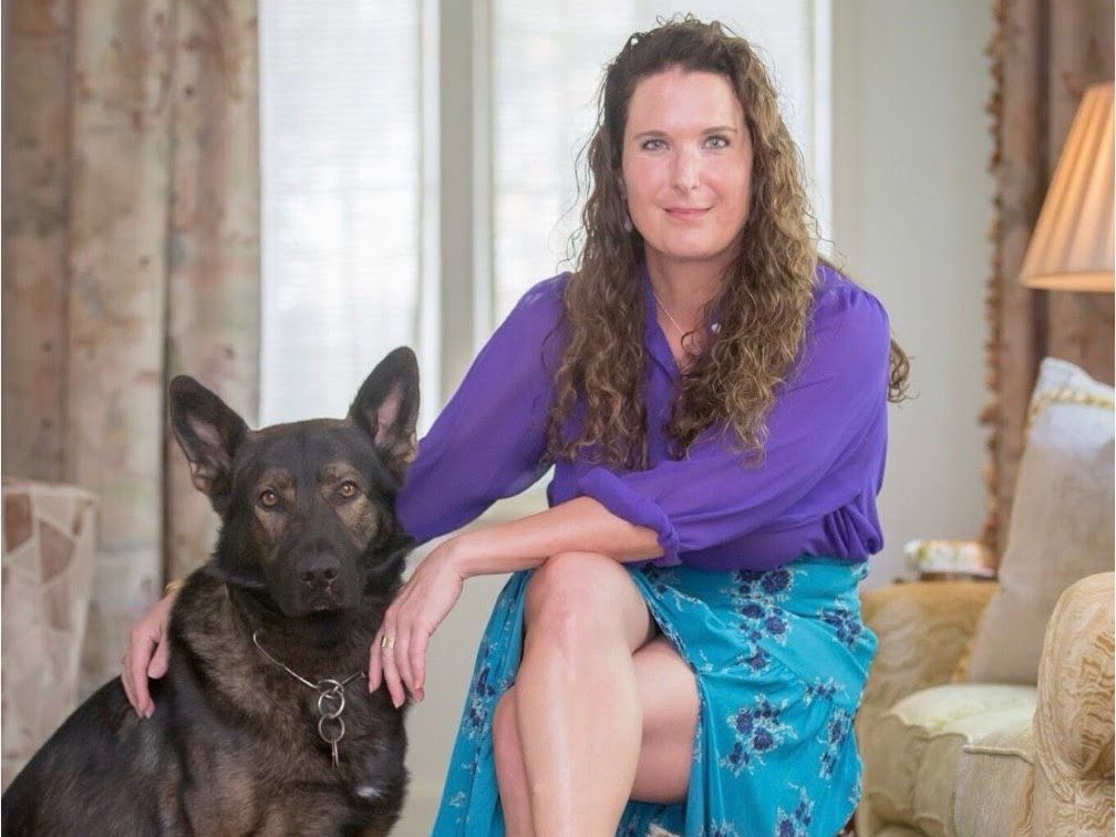 A woman is sitting on a couch next to a protection dog.