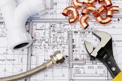 Plumbing tools and pipes on architectural blueprints.