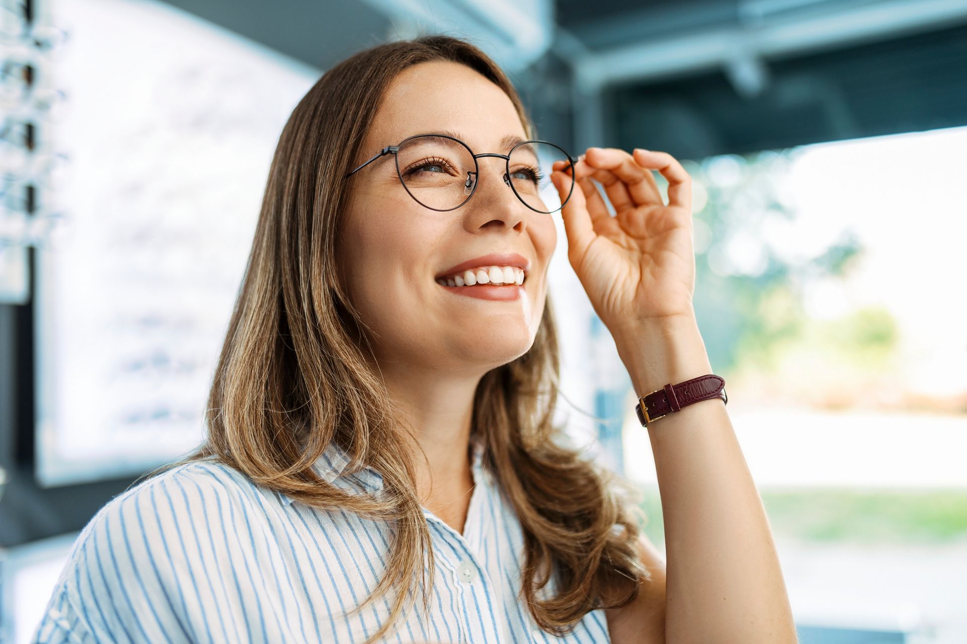 A woman wearing glasses is smiling and looking up.