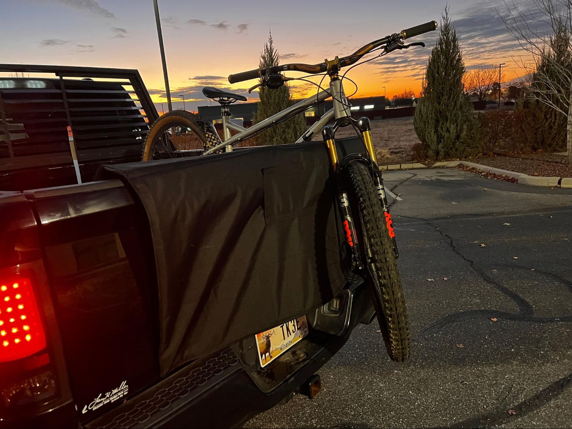 Mountain bike secured in a pickup truck bed with a tailgate pad at sunset.