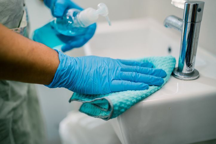 Maid cleaning wash and scrub basin in toilet at home.