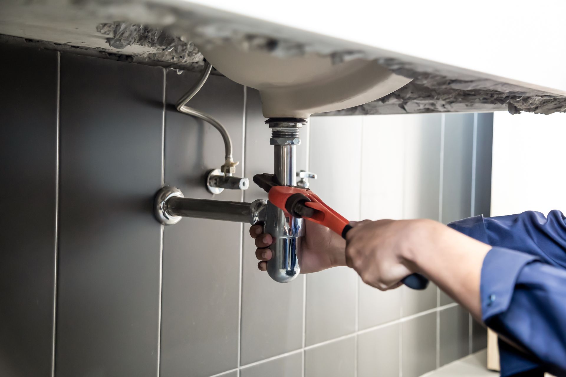 Plumbing fix in action wrench-tightening sink P-trap to prevent leaks Plumbing fix in action wrench-tightening sink P-trap to prevent leaks