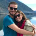 A man and a woman wearing sunglasses are hugging each other
