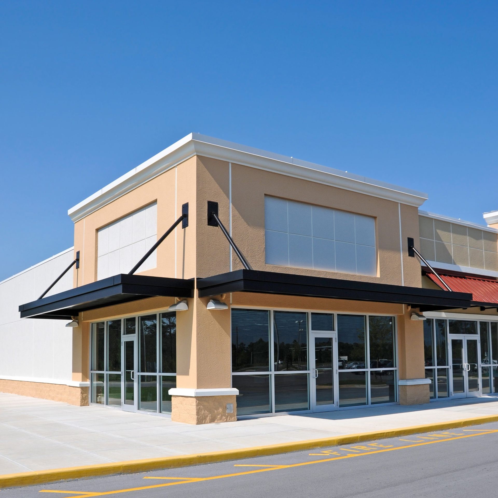 An empty beige storefront with large glass windows