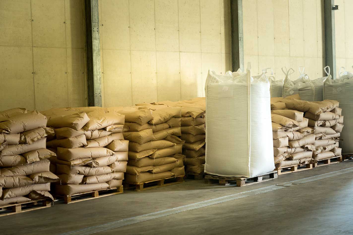 Stapel von braunen Säcken in einem Lagerhaus neben einem großen weißen Big Bag