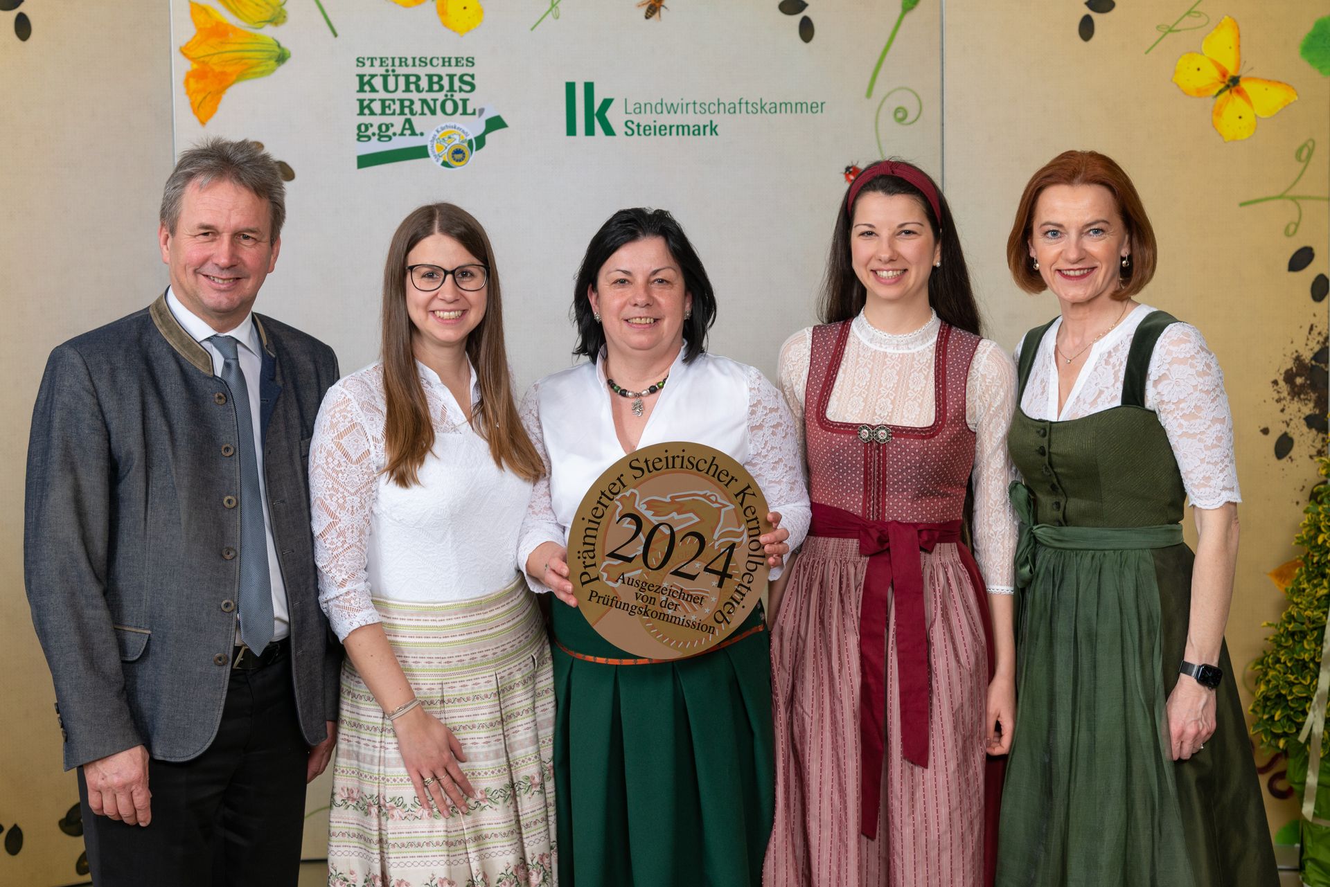 Fünf Personen posieren in einem Innenraum und halten eine Plakette mit der Jahreszahl 2024 in den Händen