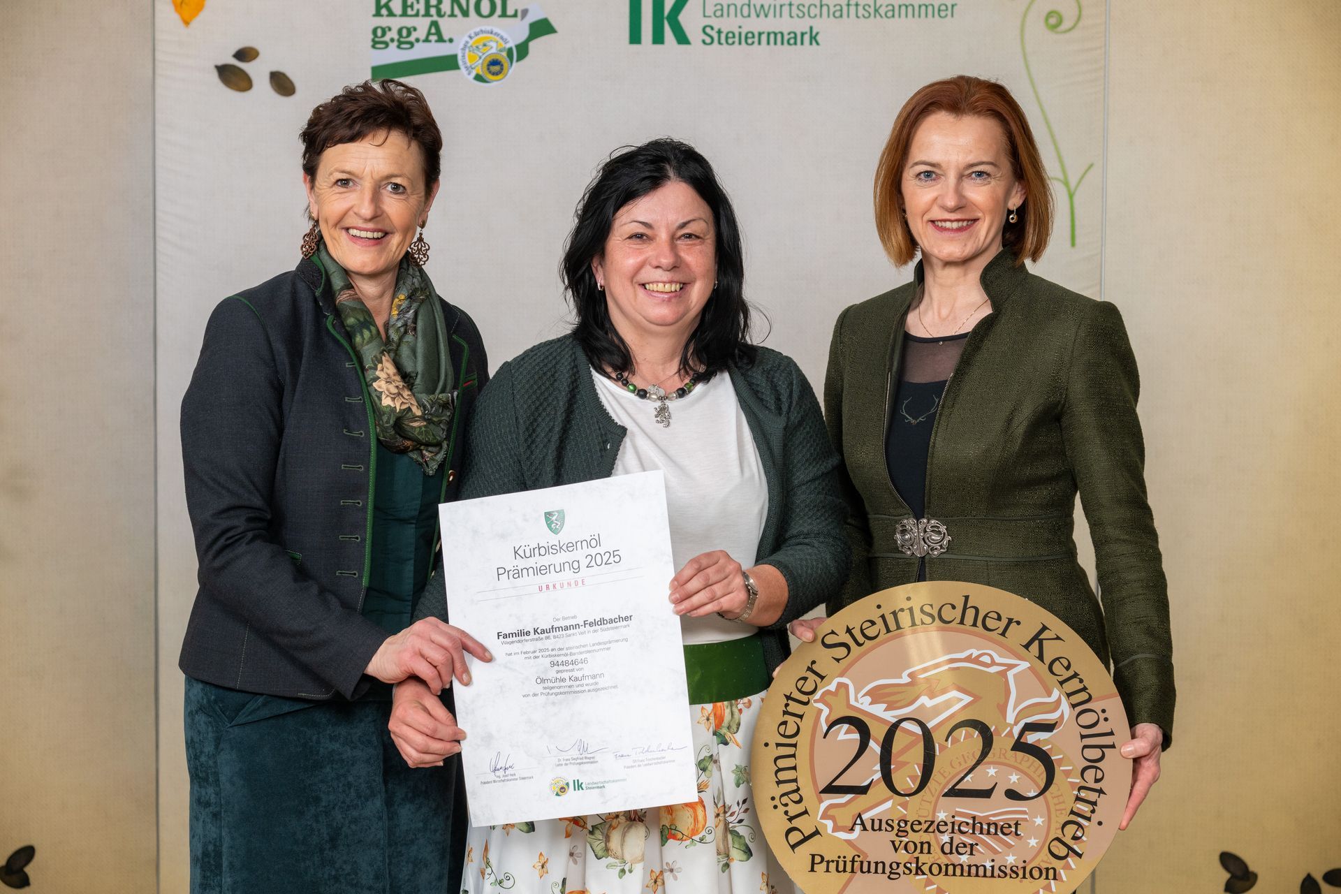 Drei Frauen posieren bei einer Preisverleihung mit einer Urkunde und einer Auszeichnungsplakette für das Jahr 2025.