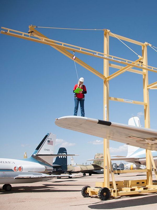 A man wearing a hard hat and safety harness is standing on top of a rocky roof.