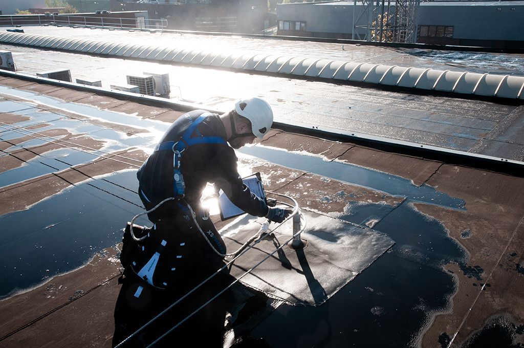 Construction worker attaching himself to rooftop anchor for fall protection
