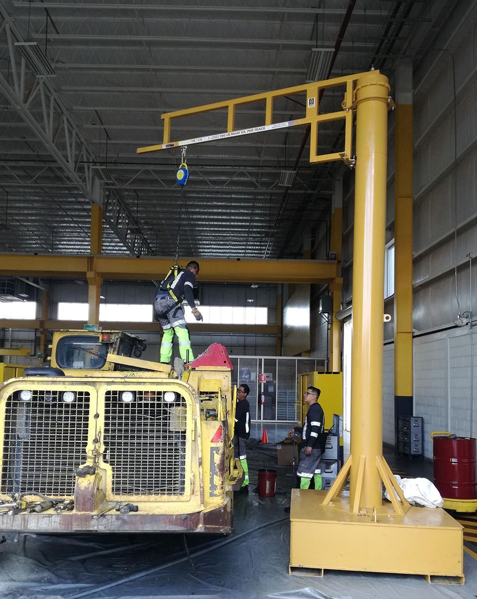 A man is standing on top of a yellow truck in a warehouse.