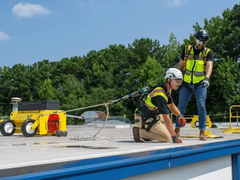 Two construction workers are working on a roof.
