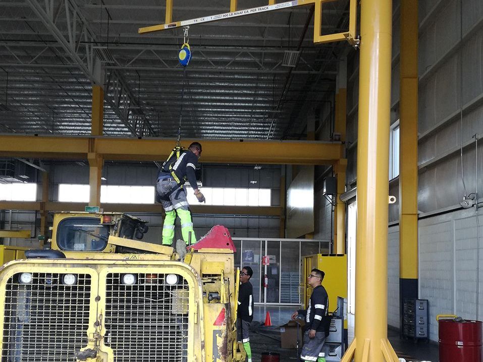 A man is standing on top of a yellow machine in a building.