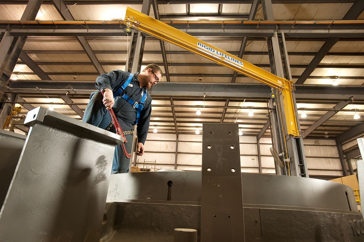 A man is working on a large piece of metal in a factory.