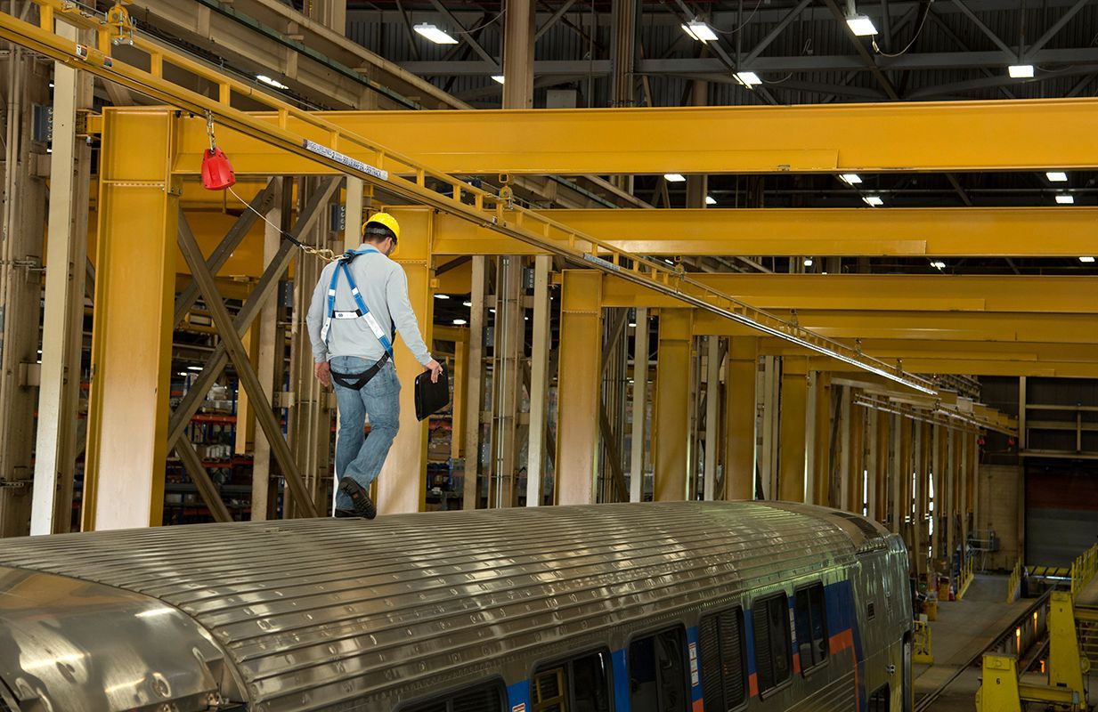 A man is standing on top of a train in a factory.