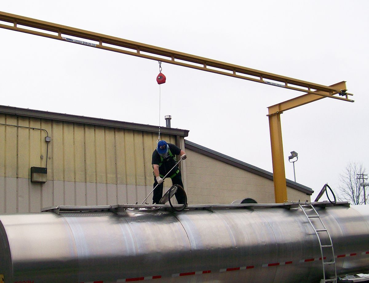 A man is standing on top of a large metal tank
