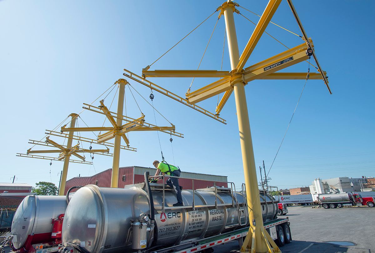 A man is standing on top of a large metal object being lifted by a crane.