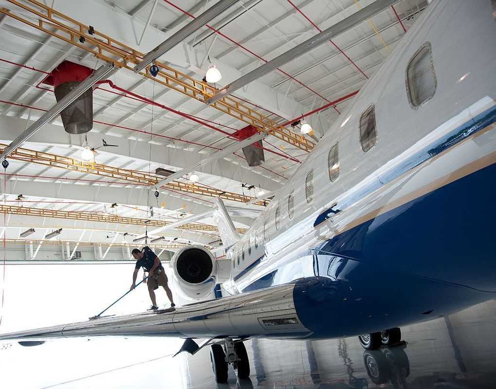 A man is cleaning the wing of an airplane in a hangar. A man is cleaning the wing of an airplane in a hangar.