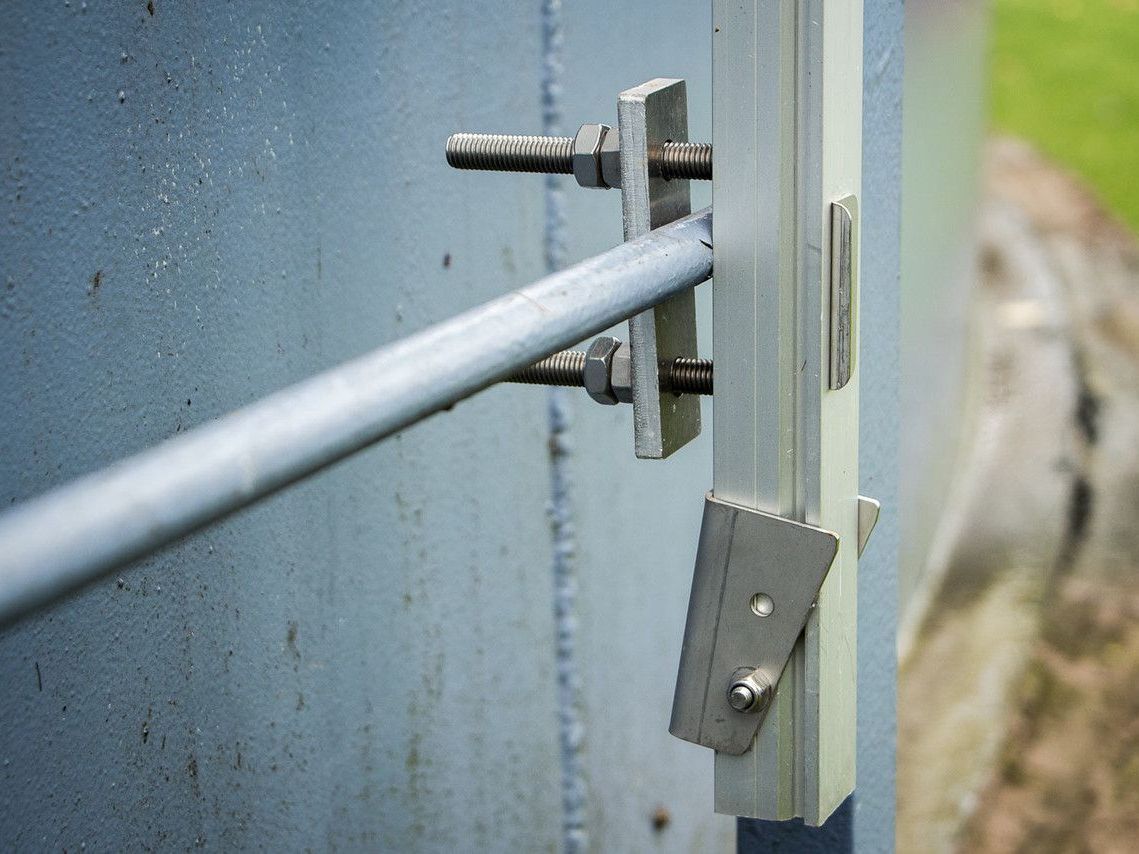 A close up of a metal fence with a metal pole attached to it.
